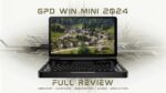 GPD WIN Mini 2024 : PC de jeu compact et portable présenté en position ouverte. L&#039;écran haute résolution de 7 pouces présente une vue aérienne dynamique d&#039;un village rural avec des maisons traditionnelles et une végétation luxuriante. Clavier complet QWERTY visible sous l&#039;écran, indiquant une double fonctionnalité pour les jeux et la productivité. L&#039;appareil est entouré de circuits imprimés stylisés, soulignant ses prouesses technologiques. Le texte superposé indique &quot;GPD WIN MINI 2024&quot; en haut et &quot;FULL REVIEW&quot; en bas, avec en sous-texte &quot;UNBOXING - OVERVIEW - BENCHMARKS - GAMES - EMULATORS&quot;. L&#039;image mélange la présentation du matériel réel avec des éléments graphiques, suggérant un examen complet des capacités de l&#039;appareil dans divers cas d&#039;utilisation. Le châssis noir contraste avec le contenu coloré de l&#039;écran, soulignant le design élégant et la portabilité de l&#039;appareil tout en promettant de puissantes performances pour les jeux et au-delà.