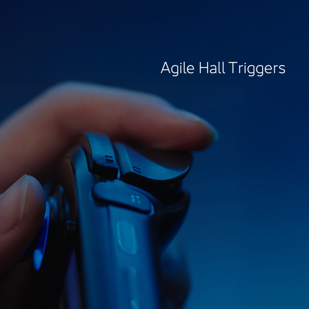 AYANEO 3 4 A close-up shot of a hand holding a dark-colored gaming controller or handheld device, specifically highlighting the shoulder trigger button. The image is bathed in a blue light, and white text at the top reads "Agile Hall Triggers."