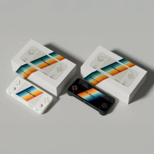 Top-down view of white and black AYANEO Pocket ACE units placed beside their respective retail packaging, each with colorful branding and console imagery printed on the box lids.