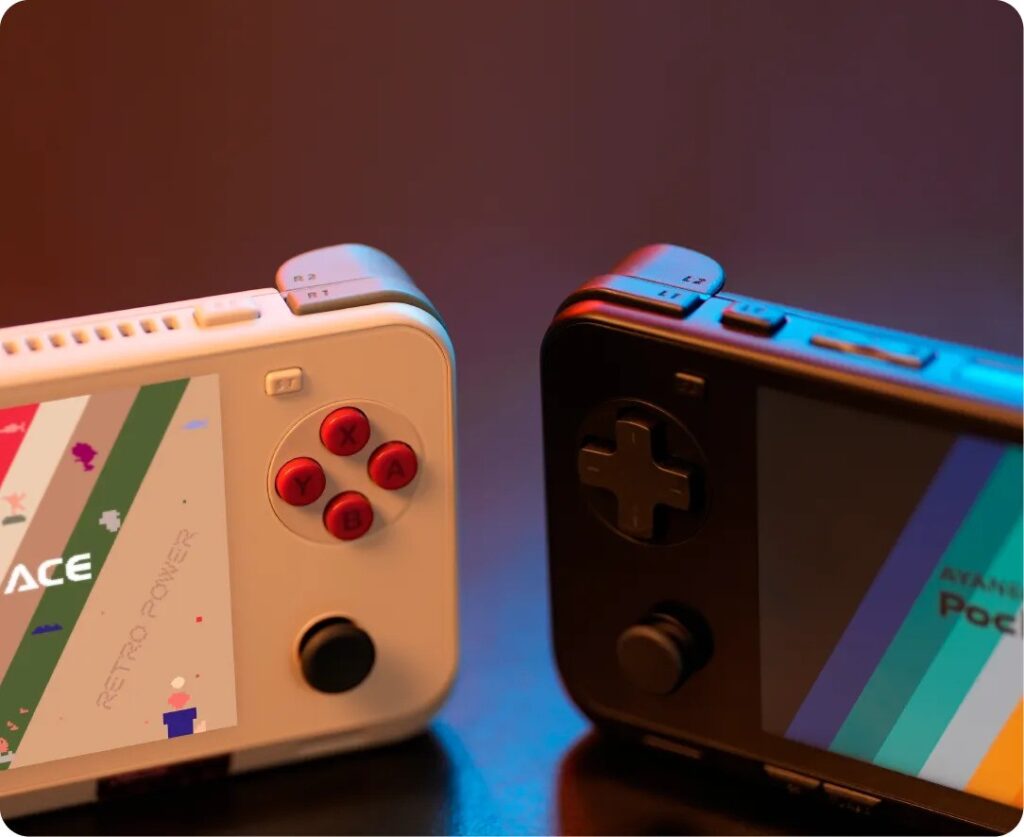 AYANEO Pocket ACE 3 Two AYANEO Pocket ACE handheld gaming consoles side by side—one white with red buttons labeled 'Retro Power', and one black with dark controls. Both display colorful striped screen graphics, showcasing different color schemes. Lit with warm and cool tones to highlight the hardware design and shoulder buttons.