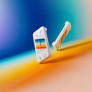 Two white AYANEO Pocket ACE units floating side-by-side against a colorful gradient background; one shows the front, the other the rear vents and side profile.